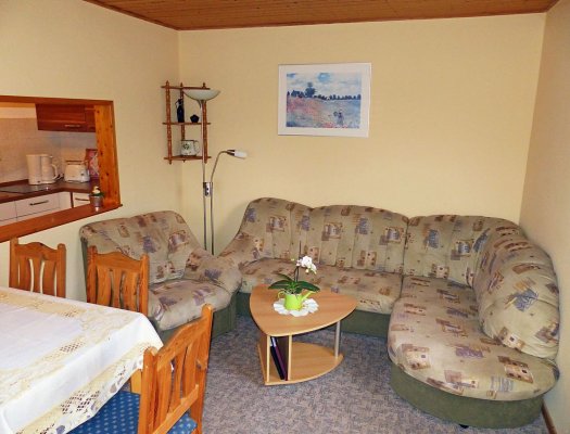 Wohnzimmer mit Esstich, Sessel und Eck-Couch